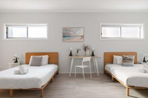 2 Betten in einem Zimmer mit einem Schreibtisch und Fenstern in der Unterkunft Comfort Stay - Detached Quadruple Studio Room with Simple Kitchenette near Top Ryde city in Sydney