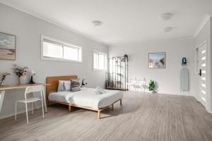 ein Schlafzimmer mit einem Bett und einem Schreibtisch und Stühlen in der Unterkunft Comfort Stay - Detached Quadruple Studio Room with Simple Kitchenette near Top Ryde city in Sydney