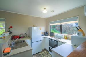 a kitchen with a white refrigerator and a window at Gateway to Adventure in Rotorua
