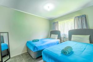 a room with two beds and a chair and a mirror at Gateway to Adventure in Rotorua