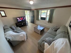 a living room with a couch and a tv at Cottages by Storybook Park in Burley