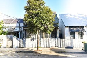 una cerca blanca frente a una casa con un árbol en Cozy Newtown Terrace, en Sídney