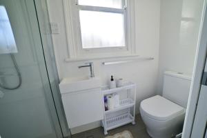 Un baño con inodoro, lavabo y ventana. en Cozy Newtown Terrace, en Sídney 5 fotos más