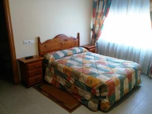 a bedroom with a bed and a dresser and a window at Hostal Carmen in El Puente