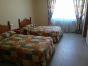 a hotel room with two beds and a window at Hostal Carmen in El Puente
