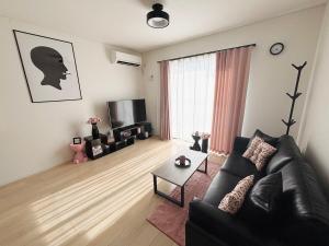 un soggiorno con divano nero e TV di ZZOKIAI緋桜 Open in September 2025! 30-second walk to the sea!4LDK!Free parking! a Sunja