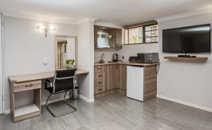a kitchen with a desk and a television in a room at Bhotani Lodge in Port Elizabeth