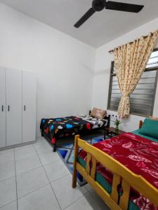 a room with two beds and a ceiling fan at Myrol Homestay Padang Serai Kulim in Padang Serai