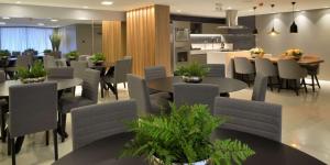 a dining room with tables and chairs and a kitchen at Loft Alto padrão na beira mar de Tambaú in João Pessoa