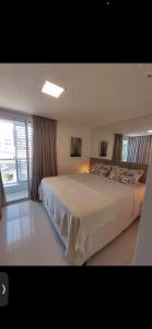 a bedroom with a large white bed with a window at Loft Alto padrão na beira mar de Tambaú in João Pessoa