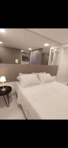 a bedroom with a large white bed and a table at Loft Alto padrão na beira mar de Tambaú in João Pessoa +33 photos