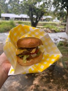 a person holding a sandwich in a paper wrapper at Al Sakinah Resort in Bentong