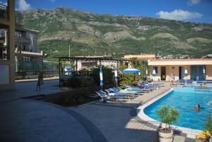 a resort with a pool and chairs and a mountain at Vila Laguna in Sutomore