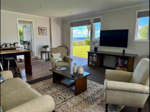 a living room with a flat screen tv and furniture at The Lake House with private spa Lake Rotorua in Rotorua