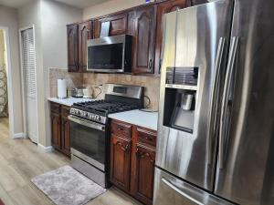 a kitchen with stainless steel appliances and wooden cabinets at Complete Home with everything in The Colony