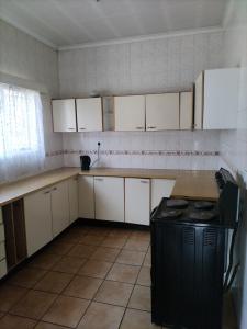 una pequeña cocina con armarios blancos y un aparato negro en Foxtrot Guest House, en Pretoria