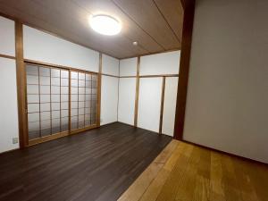 une pièce vide avec des murs blancs et du parquet dans l'établissement eyehouse ozu No1, à Ozu