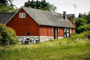 a red barn with a gray roof at Rubensholm Bed & Breakfast in Brösarp