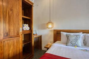a bedroom with a bed and a wooden cabinet at Kampuak Cottages in Nusa Penida +43 photos