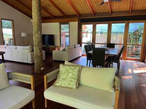 a living room with couches and a table and chairs at Lux rainforest lodge - 2 King bedrooms in Jogo