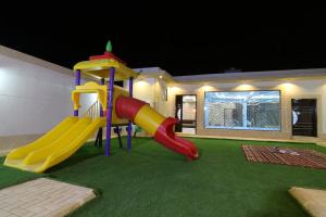 un parque infantil con un tobogán en una casa en Dorrat Al Nakheel Chalet, en Buraidah