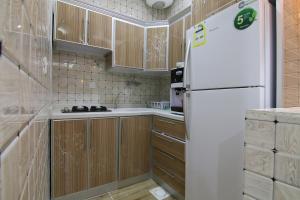 a kitchen with wooden cabinets and a white refrigerator at Dorrat Al Nakheel Chalet in Buraydah