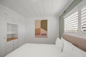 a white bedroom with white cabinets and a window at The Avenue - Fremantle 3 Bed in South Fremantle