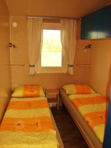 two beds in a small room with a window at Mobilehouse & Camping Lijak in Šempas