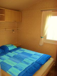 a bedroom with a blue bed with a window at Mobilehouse & Camping Lijak in Šempas