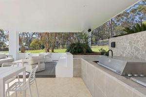 een terras met witte stoelen en tafels en een keuken bij La La Land by Coast Hosting in Tascott