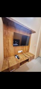 a television on a wooden shelf with two remote controls at Hotel Vrindavan - The Premium Krishivaa - Near Prem Mandir - Chaar Dhaam - in Vrindāvan