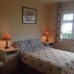 1 dormitorio con 1 cama, 2 lámparas y ventana en Seaside Accomodation, en Quilty