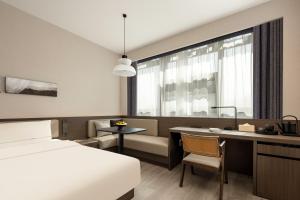 a hotel room with a bed and a desk and a window at Atour Hotel Yintai Department Store at Wenzhou South Station in Wenzhou