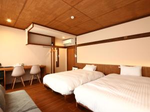 a bedroom with two beds and a desk and a table at nirasakiyaSTAY in Nirasaki
