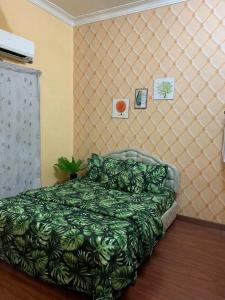 a bedroom with a green bed and a couch at Purnama Homestay in Kampong Bukit Badong