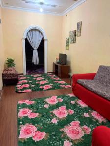 a living room with a red couch and flowers on the floor at Purnama Homestay in Kampong Bukit Badong
