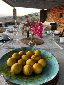 a plate of lemons on a table with a vase of flowers at Tzia Blue in Koundouros