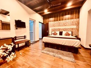 ein Schlafzimmer mit großem Bett und Fernseher in der Unterkunft Nature Valley Farmhouse Resort by Raarees, Munnar #lap of nature #premium rooms #parking #Scenic view #garden with fireplace #property of the year in Munnar