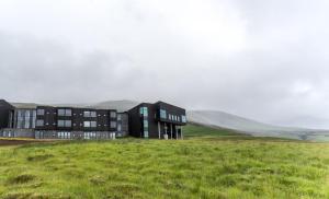 un edificio negro en un campo con montañas en el fondo en Fosshotel Glacier Lagoon en Hnappavellir