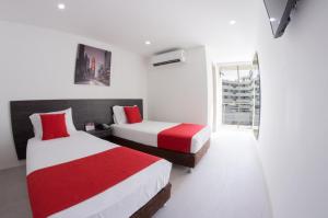 1 dormitorio con 2 camas con sábanas rojas y blancas en Massay Hotel, en Neiva