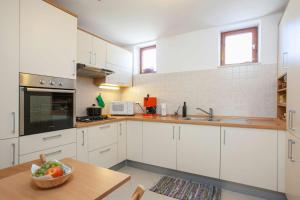 a kitchen with white cabinets and a bowl of fruit on a table at Holiday Home Luma in Podgora