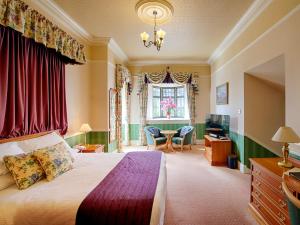 a bedroom with a bed and a desk and a window at Kincraig Castle Hotel in Invergordon