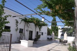 un patio con sedie e tavoli e un edificio di La Ferula Bed&Pool a Santeramo in Colle