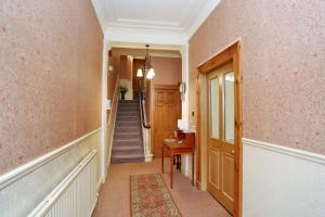 a hallway with pink walls and a staircase with a desk at Butlers Guest House in Aberdeen