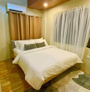 a bedroom with a large white bed and a window at The Bali Farm in Cabuyao