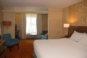 a hotel room with a large bed and a chair at Comfort Inn & Suites in Watervliet