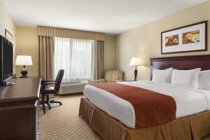 ロックヒルにあるCountry Inn & Suites by Radisson, Rock Hill, SCの大きなベッドと机があるホテルの部屋