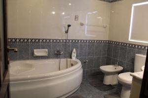 ein Badezimmer mit einer weißen Badewanne und einem WC in der Unterkunft South Village Townhouse in Żabbar