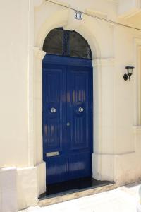 a blue door in a white building with an arch at South Village Townhouse in Żabbar