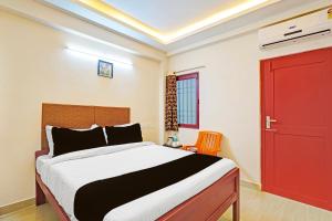 a bedroom with a bed and a red door at Hotel O Purasaiwalkam in Chennai